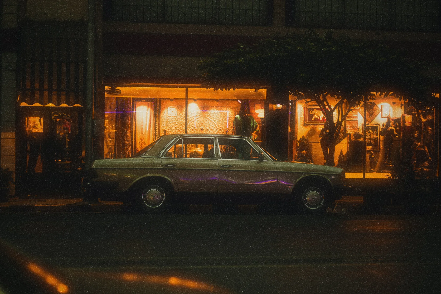 A car outside a lit restaurant at night, developed in Amber