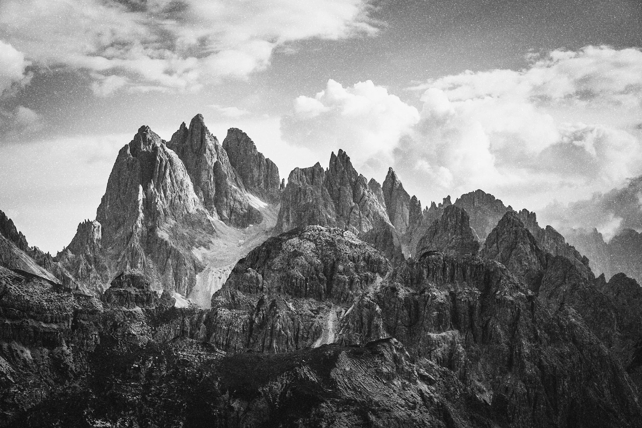Jagged Dolomite peaks under heavy clouds in black and white, framed 3:2